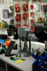 Modelo de AT-AT impresso em 3D, numa bancada com outras peças