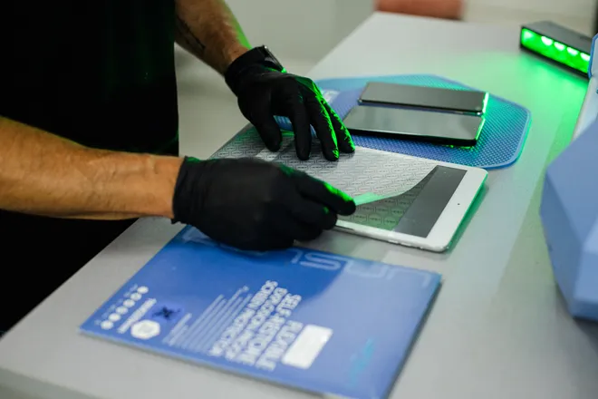 Técnico de luvas a aplicar uma película num tablet