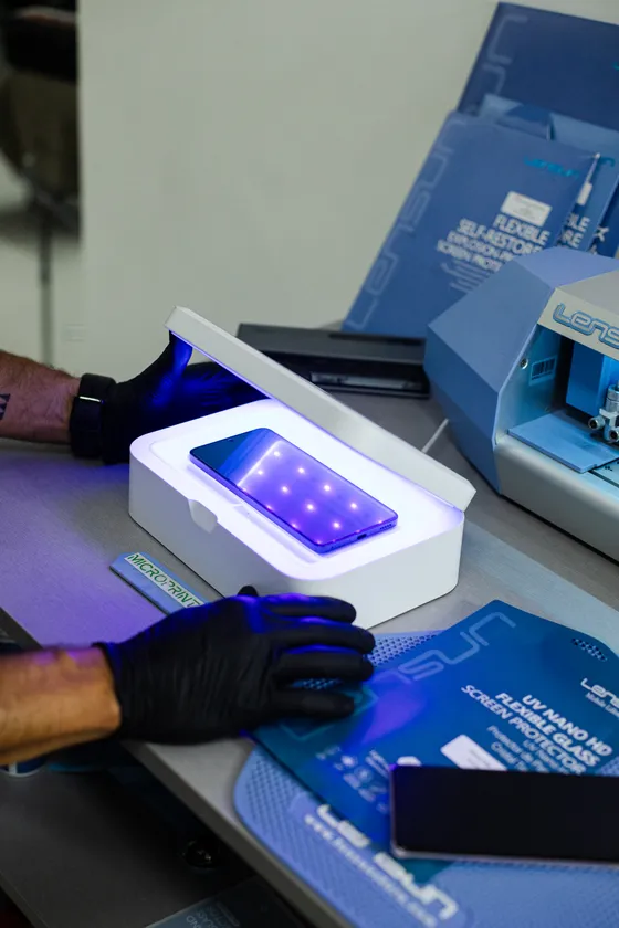 Película a curar numa caixa de luz ultravioleta, ao lado de um telemóvel