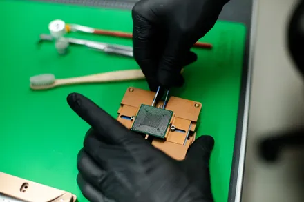 Mão de luva a segurar um chip BGA sobre a bancada